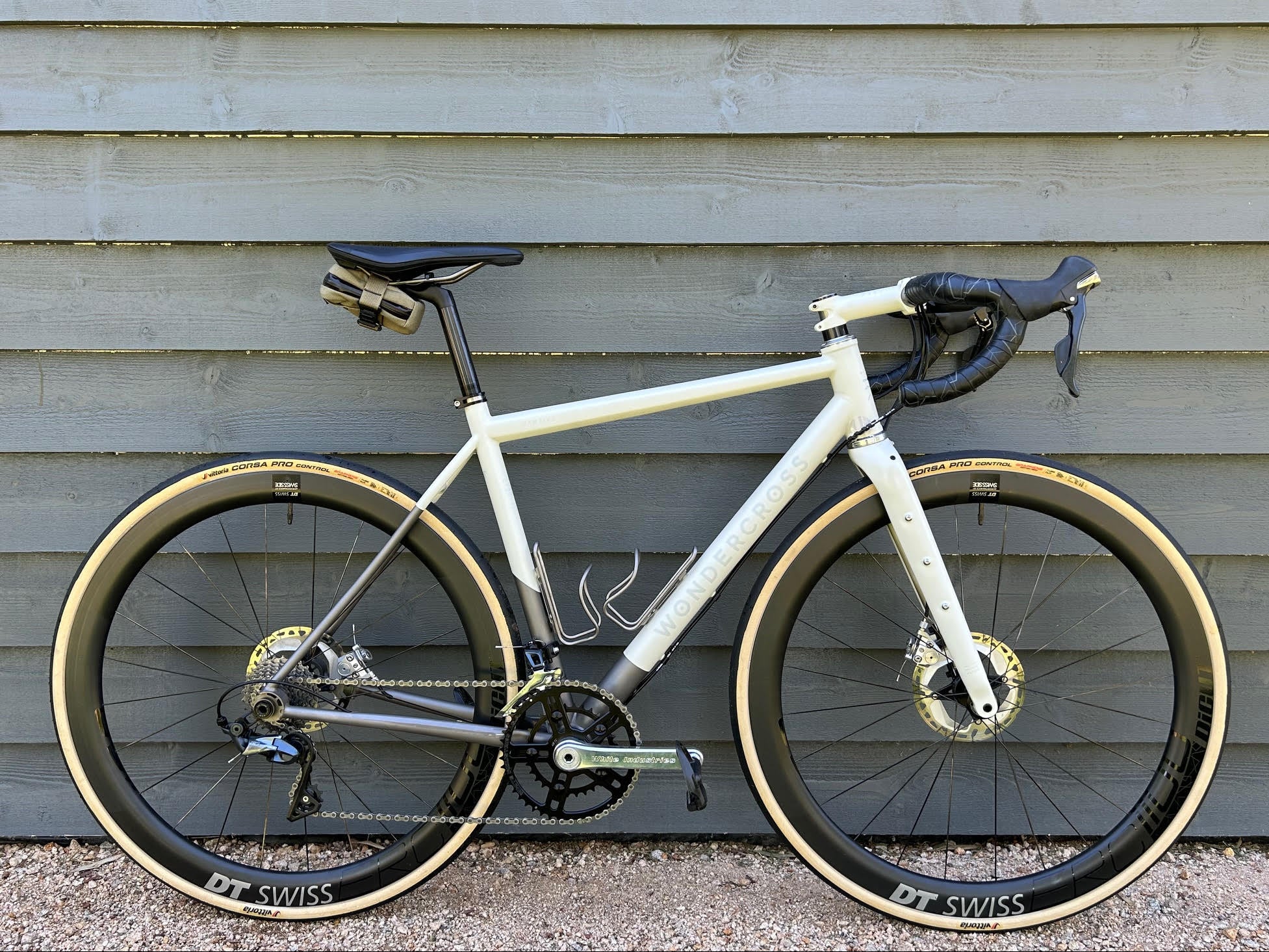 White bicycle with black tires against a wooden wall